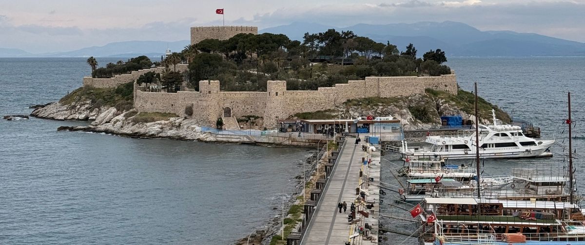 El dique peatonal que une Kuşadası con la isla de las Palomas y su fortaleza, con barcos de excursión amarrados a la derecha